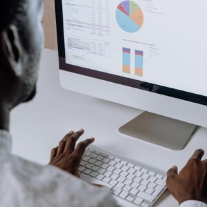 Businessman analyzing charts and data on desktop computer in office setting.