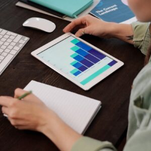 Focused person working on digital tablet analyzing business graphs at desk.